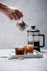 A woman pouring almond milk into iced cold brew coffee — Photo de stock