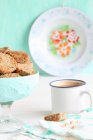 Glass bowl of biscuits with coffee in enamel cup — Stock Photo