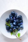 Blueberries with blue flowers in small bowl — Stock Photo