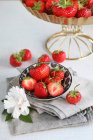 Frische ganze und halbierte Erdbeeren in Schüssel, dekoriert mit Papierblume — Stockfoto