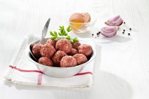 Raw meatballs, broken eggs, onions and spices — Stock Photo