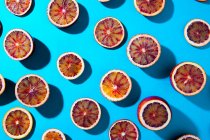 Mitades de naranja sangre sobre fondo turquesa - foto de stock