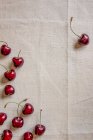 Fresh cherries on white cloth surface — Stock Photo