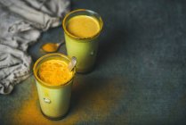 Goldene Milch mit Kurkumapulver in Gläsern vor dunklem Grunge-Hintergrund — Stockfoto