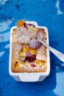 Clafoutis pie with apricots and cherries with powder sugar and spoon in tin — Stock Photo