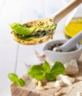 A wooden spoon with pesto and a basil leaf — Stock Photo