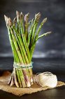 Mazzo di asparagi legati con spago da cucina, su un pezzo di sacco di canapa — Foto stock