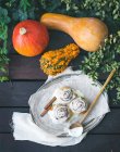 Cinnamon pumpkin buns with creamy cheese icing and ripe pumpkins over a dark wood background — Stock Photo