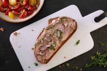 Slice of bread spread with liver pate and spring onions served with tomato salad — Stock Photo