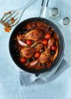 Mediterranean chicken legs with ingredients and sauce in pan with cruet — Stock Photo