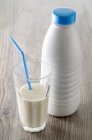 Стакан молока с соломой и бутылкой молока — стоковое фото