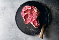 Roh-Rindersteak mit Messer auf metallischem Hintergrund — Stockfoto