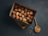 Vista superior de nueces frescas en una caja de madera sobre un fondo negro - foto de stock