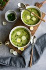 Traditional Frankfurt green herb soup with quail eggs and chives in bowls on a wooden board — Stock Photo
