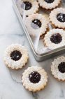 Linzer Pltzchen, jam sandwich biscuits on marble surface and in tin — Stock Photo
