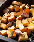 Raw pumpkin pieces with garlic, sage and thyme in a roasting tray — Stock Photo