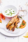 Lemony Marinated Chicken Skewers on a white plate, served with sesame seeds, orange pieces and fresh herbs — Stock Photo
