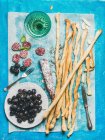 Italian Grissini bread sticks, dry cured pork meat sausage, black olives in white plate and white wine — Foto stock