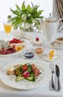 Ein Frühstückstisch mit Prosciutto, gemischten Blättern, Balsamico-Essig, Brot und Butter, Gurken, Radieschen, einem weich gekochten Ei und einem Käseteller — Stockfoto