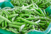 Fresh pea pods in a cardboard dish on a market stand — Stock Photo