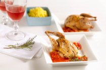 Fried quail on tomato sauce with saffron risotto — Stock Photo