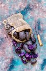 Пурпурный картофель в сумке и нож для чистки — стоковое фото