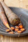 Lila Bio-Karotten, teilweise in Scheiben geschnitten — Stockfoto