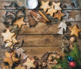 Gingerbread cookies, sugar powder, nuts, spices, baking molds, wooden angels and fir branch with colorful balls on rustic wooden background — Stock Photo