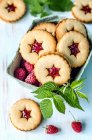 Biscuits with raspberries and mint leaves in box and on table — Stock Photo