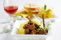Curry d'agneau sur paille de pomme de terre servi avec cornichons de mangue, vin de rose et oeufs de Pâques — Photo de stock