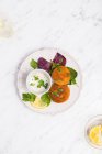 Tortini di pesce su piatto bianco serviti con yogurt greco, limone ed erbe fresche — Foto stock