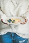 Colpo ritagliato di donna che tiene il piatto di porridge di farina d'avena con bacche, mela e mandorle — Foto stock