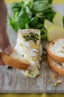 Brie cheese with honey, pistachios, hand holding baguette piece — Stock Photo