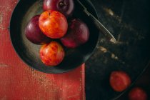 Fresh plums in black pan with knife — Stock Photo