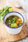 Vegetable broth in an enamel cup — Stock Photo