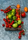 Ripe tomatoes in a bowl with fresh basil on gray background. top view. healthy food — Stock Photo