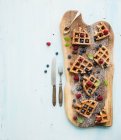 Soft Belgian waffles with berries, honey and mint on rustic wooden serving board over light blue background — Stock Photo