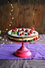 Biscuit cake with forest fruits and cream on a stand — Stock Photo