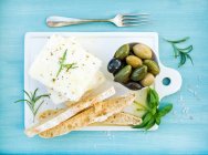 Свежий сыр фета с оливками, базиликом, розмарином и ломтиками хлеба — стоковое фото