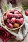Plums in wicker basket on rustic cloth with leaves and knife — Stock Photo