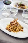 Noodles with bacon ragout and dried pear slices — Stock Photo
