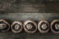 Row of portobello mushrooms on a wooden surface — Stock Photo