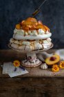 Павловский торт с персиками, карамельным соусом и просеиванием сахарной пудры — стоковое фото