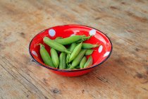 Fresh pea pods in an enamel bowl — Stock Photo
