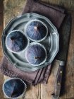 Fresh figs in wraps on metal plate and on table with cloth and knife — Stock Photo
