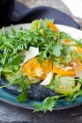 Black pizza with activated charcoal, green and yellow tomatoes, Parmesan cheese and rocket — Stock Photo