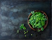 Fresh pea pods in a wooden bowl — Stock Photo