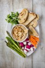 Hummus dip con sésamo, servido con pan plano y verduras crudas - foto de stock