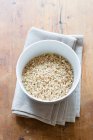 Raw white rice in a bowl on a wooden background — Stock Photo