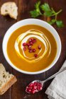 Cream of pumpkin soup with pomegranate seeds in a white bowl — Stock Photo